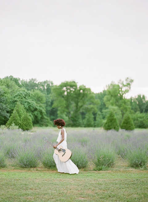 Girl walking through lavender field with guitar